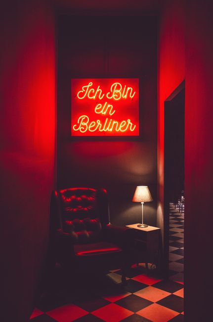 Stylish dimly lit interior featuring a neon sign above a leather armchair and table lamp.