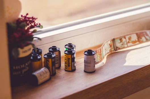 A collection of Kodak film rolls placed on a sunny window sill. Perfect for photography enthusiasts.