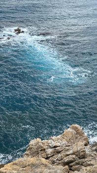 Stunning view of a rocky coastline with clear blue ocean waves crashing against the shore.