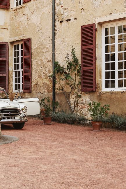 A vintage car parked in a quaint courtyard in Beaujeu, France.