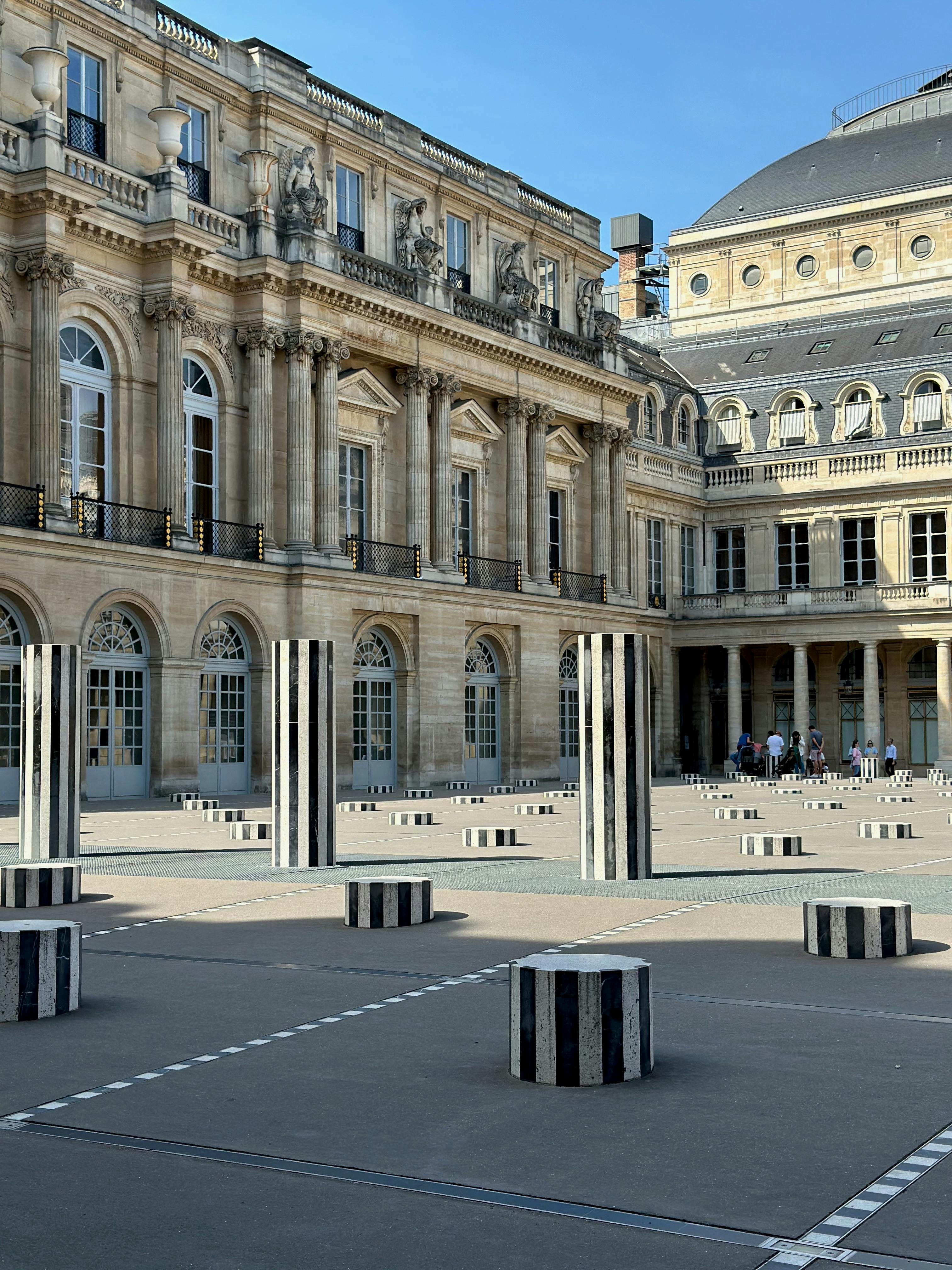 View of Palais Royal courtyard featuring modern art sculptures on a sunny day in Paris, France.