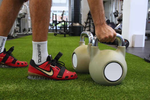 Athlete performing kettlebell workout in a modern gym setting.