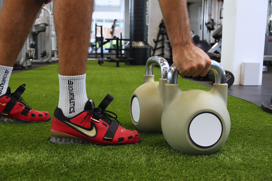 Athlete performing kettlebell workout in a modern gym setting.