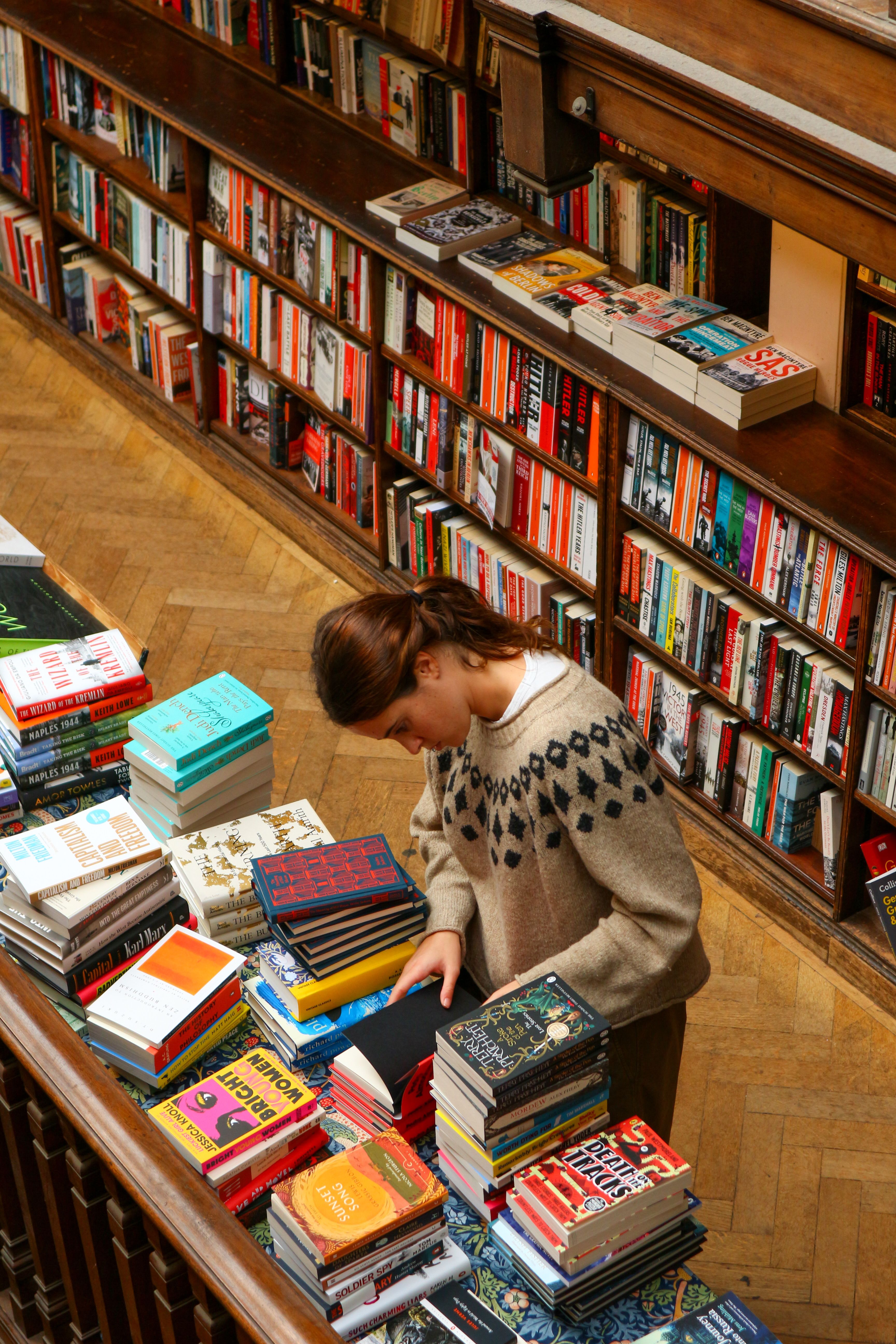 Young Woman Browsing Books in Cozy Library · Free Stock Photo