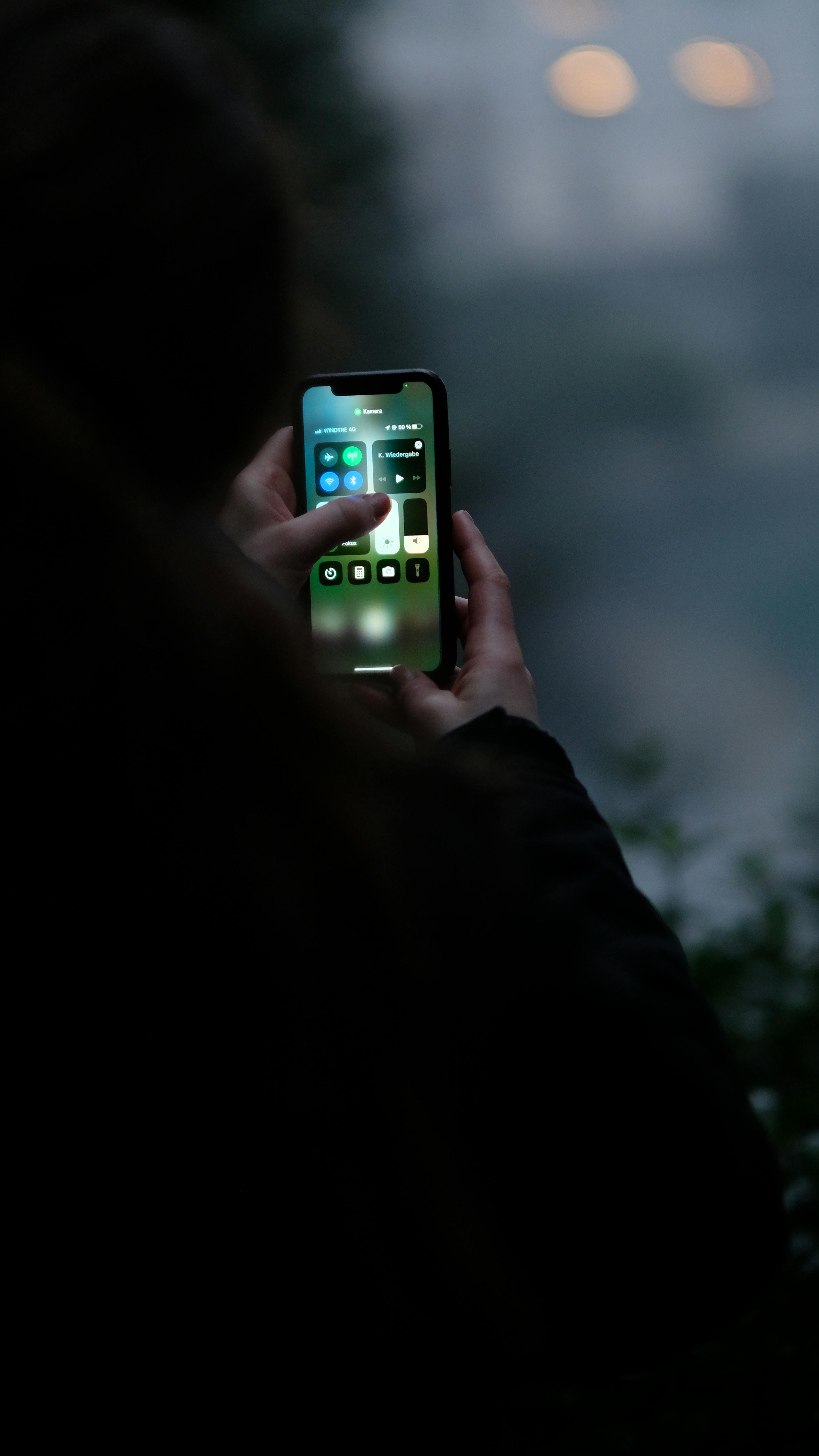 Free Close-up of hands using a smartphone outdoors in dim light conditions, perfect for tech and lifestyle themes. Stock Photo