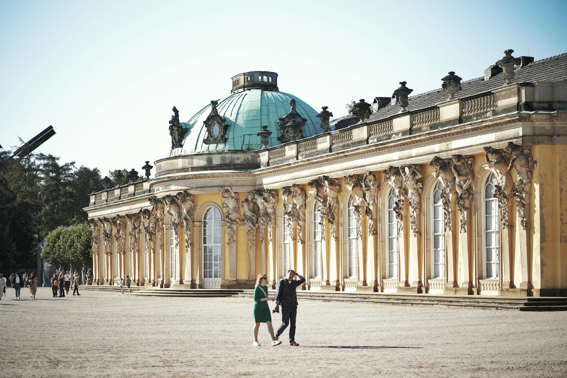 View of Sanssouci Palace in Potsdam with visitors on a sunny day.