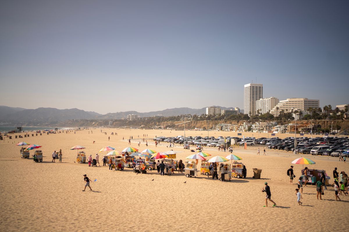 Sunny day on Santa Monica beach with vendor stalls and people strolling
