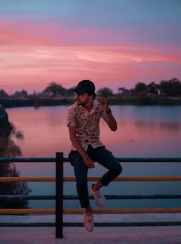 日落时分，一位时尚男士在宁静的湖边摆出时尚的姿势