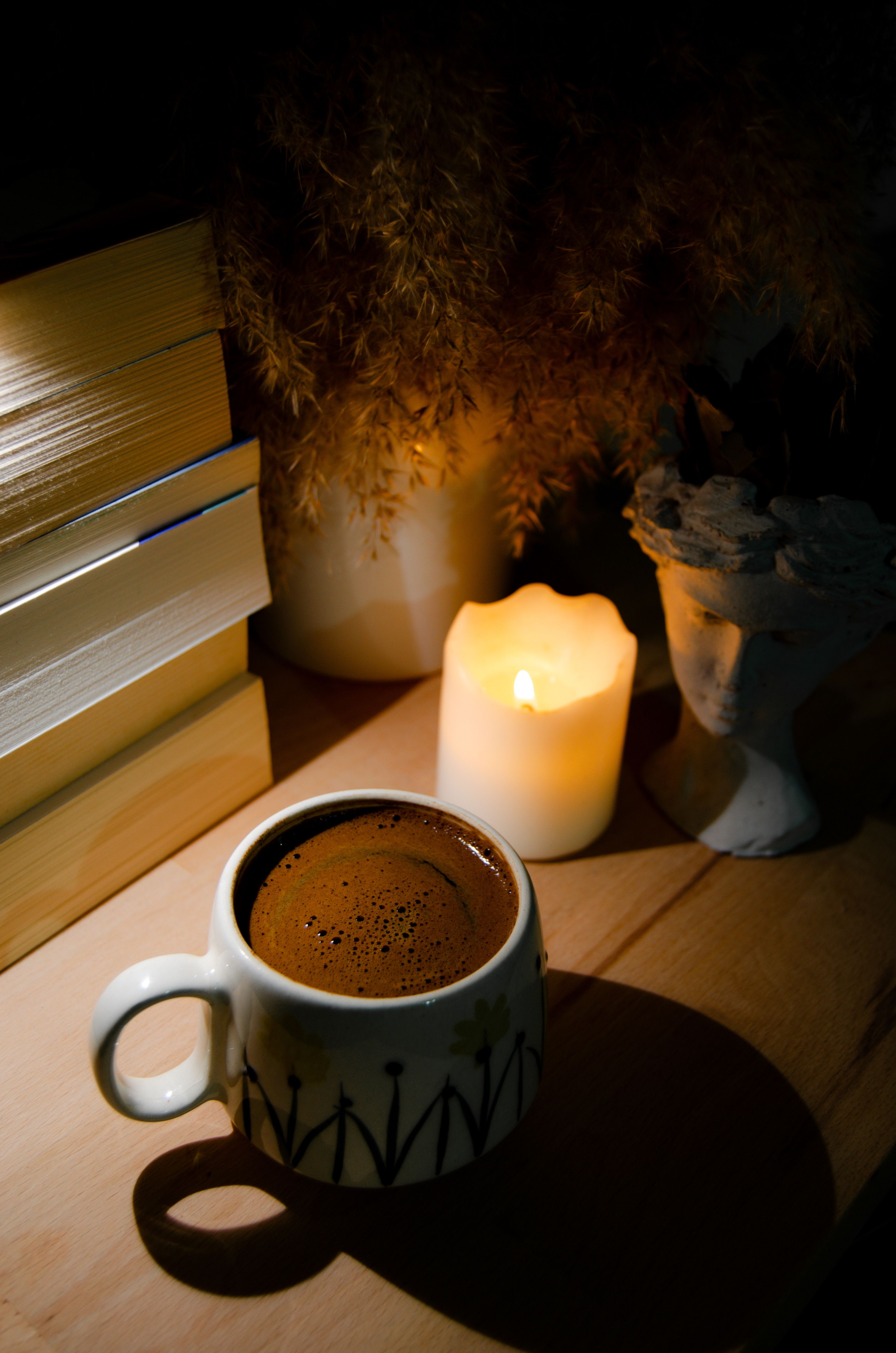 Warm coffee cup beside a glowing candle offers a cozy, relaxing setting.