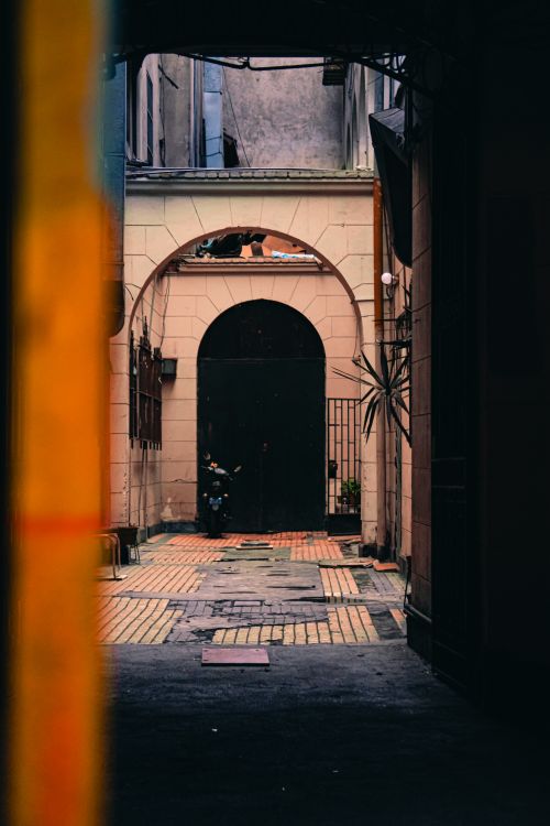 Free A moody alley with arched doorways and textured walls. Stock Photo