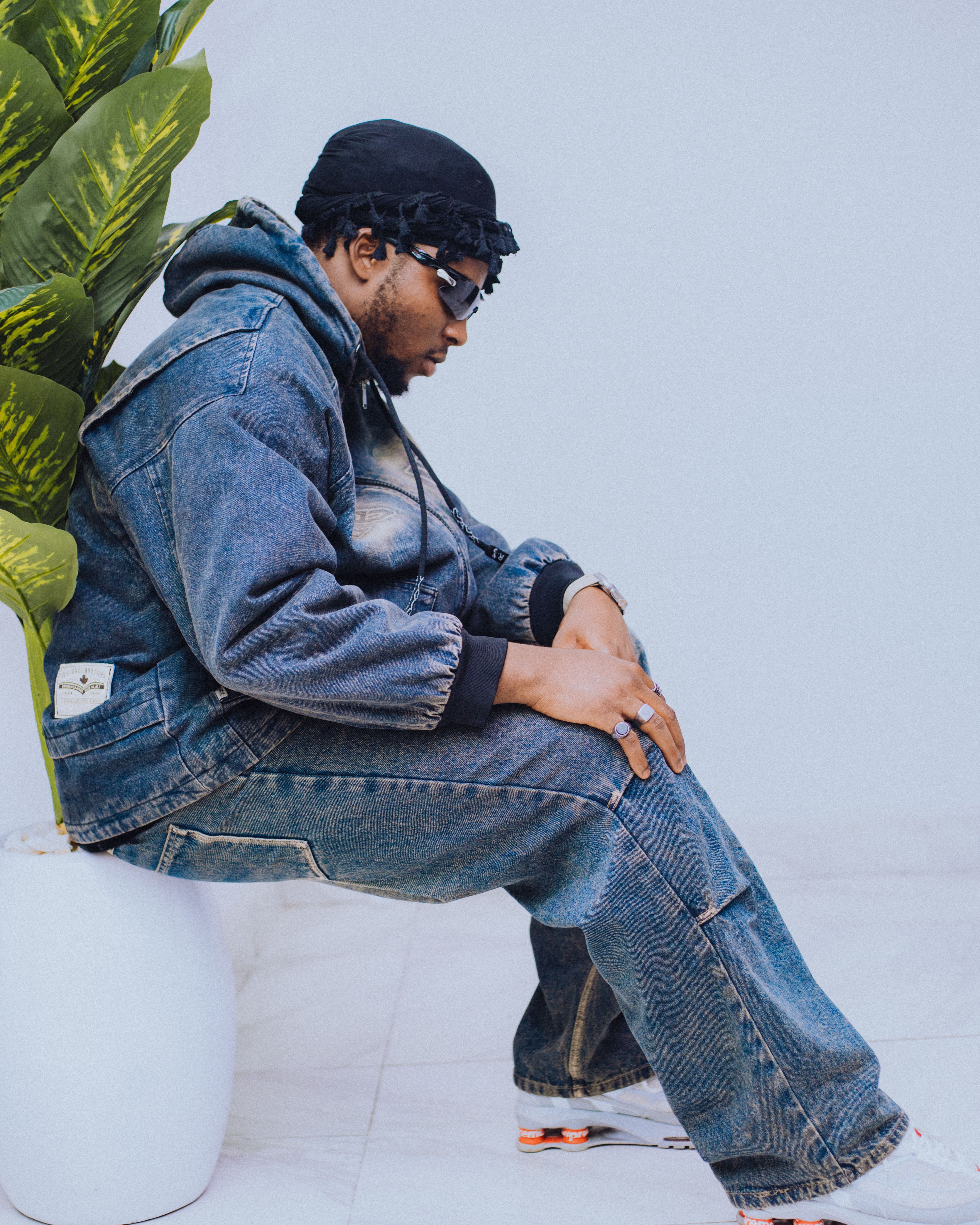 Trendy denim outfit with sunglasses and beanie in an urban setting.