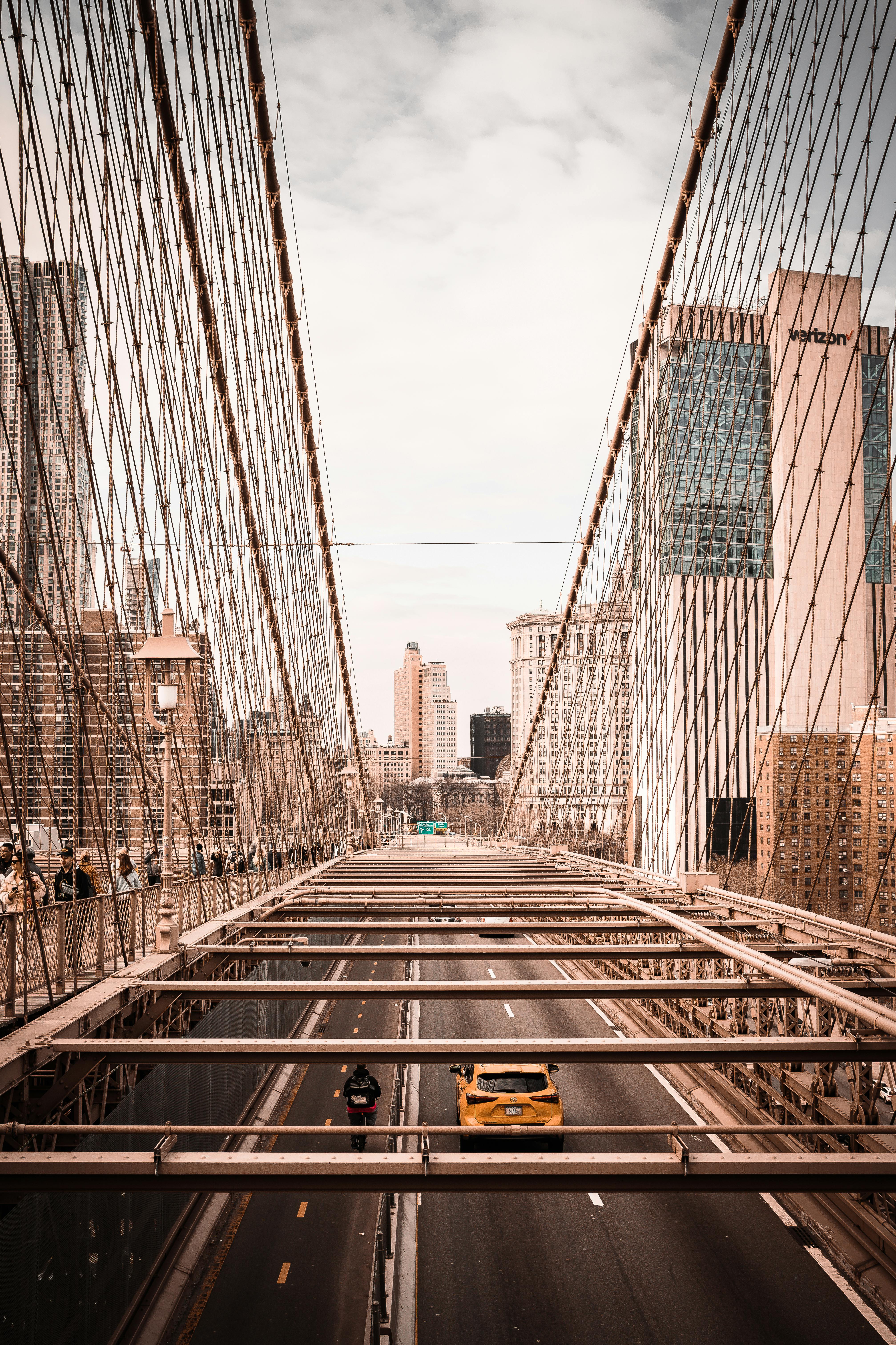 Aerial view of the Brooklyn Bridge with traffic, set against a city skyline on a clear day.