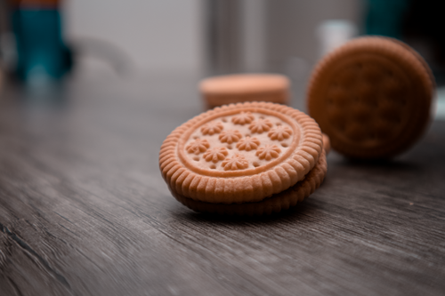 Free Close-up image of cream-filled cookies stacked on a wooden surface. Stock Photo