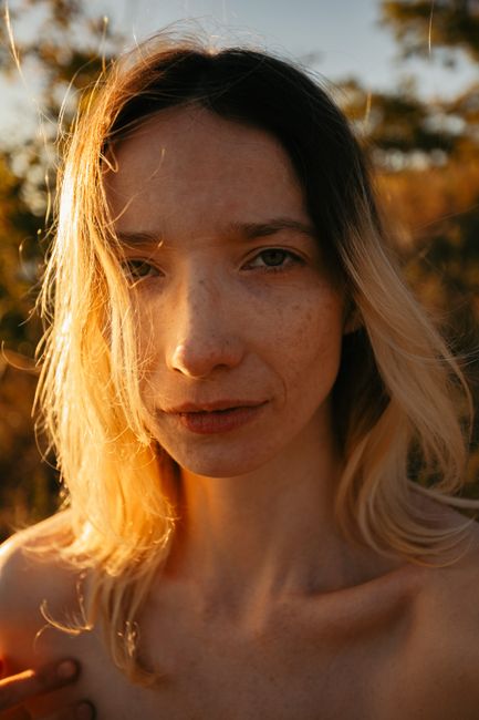 Close-up portrait of a woman during golden hour with sunlight illuminating her face.