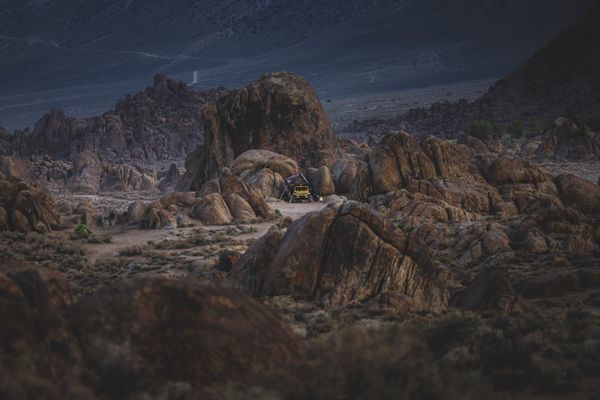 Yellow SUV camping amidst rugged rock formations