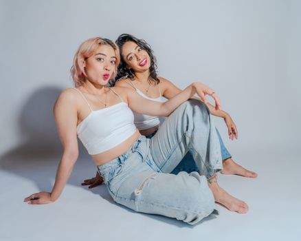 Two young women in casual attire sit together, showcasing friendship and style.