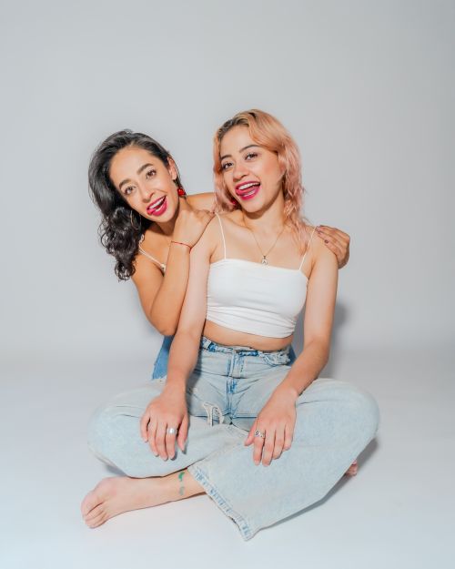 Free Two women sitting and smiling in bright studio, representing friendship and empowerment. Stock Photo