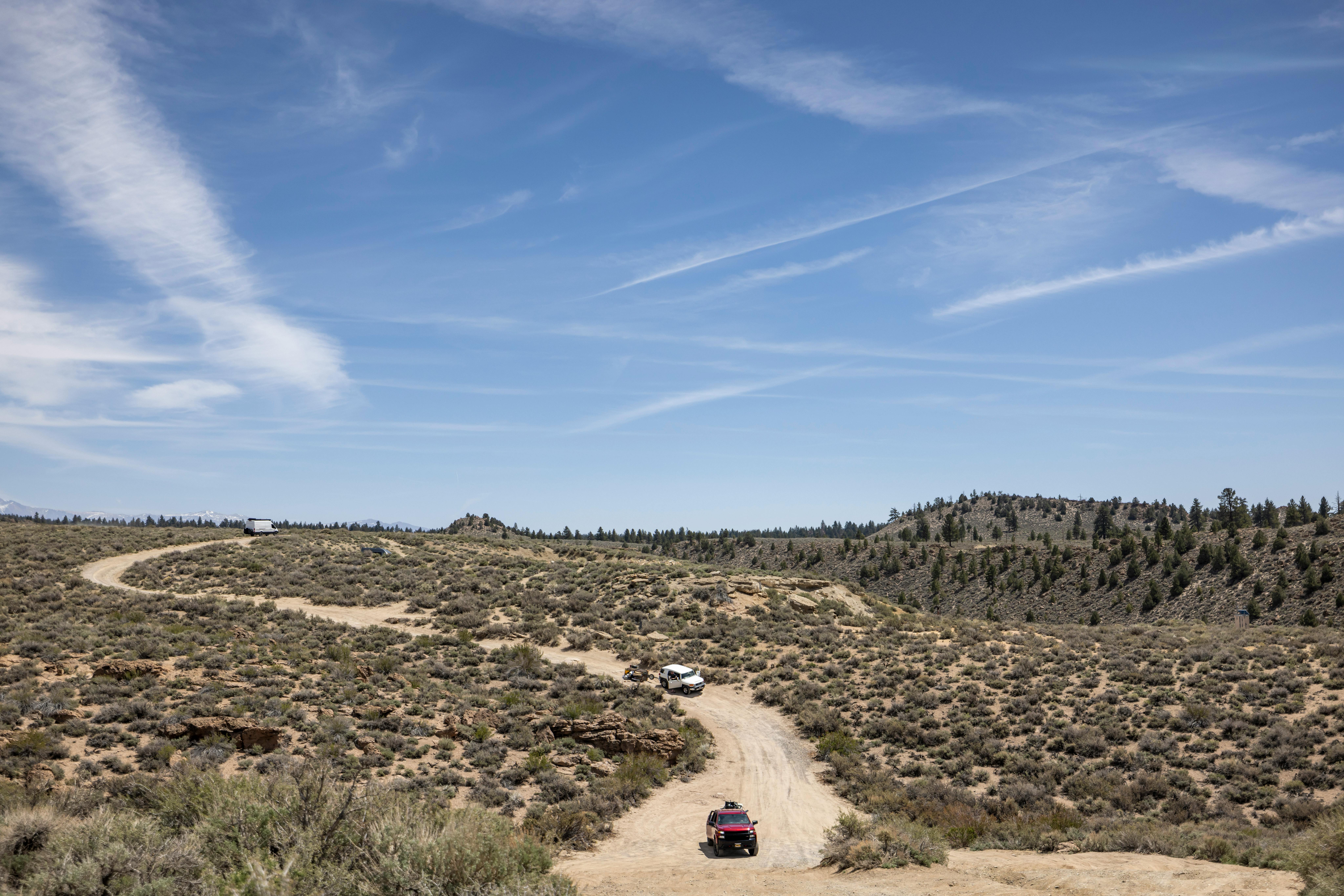 Scenic desert landscape with off-road vehicles on a dirt trail under a clear sky.