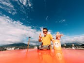 一名快乐的男子戴着太阳镜，在充满活力的蓝天下，开玩笑地对着无人机控制器摆姿势