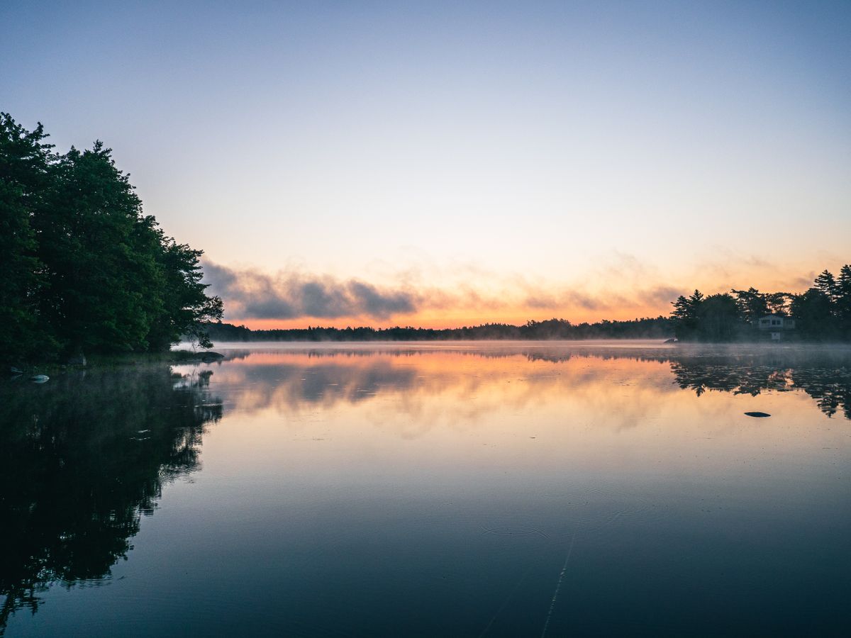 Serene morning lake landscape at sunrise with golden light reflecting on calm water, symbolising the Ayurvedic practice of waking during Brahma Muhurta