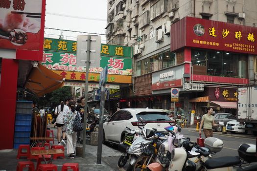 Lively urban scene capturing people, shops, and motorbikes in an Asian city street.
