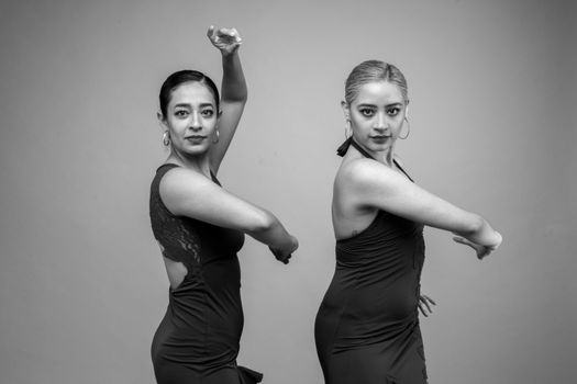 Black and white photo of two female flamenco dancers in traditional poses.