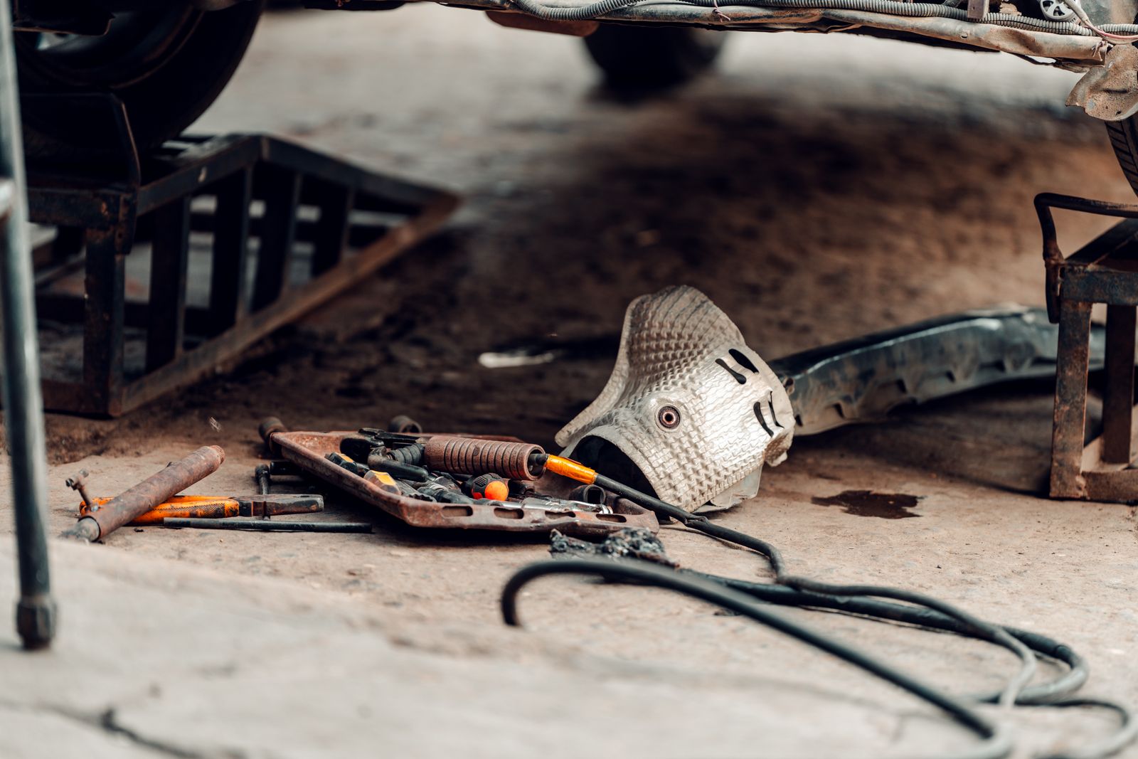 Automotive repair tools arranged beneath a vehicle in a workshop service area