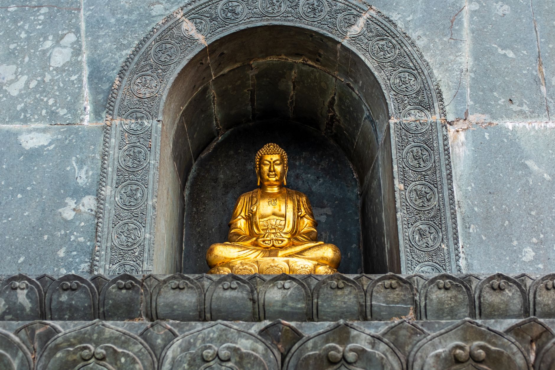 A golden Buddha statue set in ornate stone architecture in Lao Cai, Vietnam.