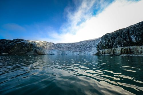 Free Stunning view of an Arctic glacier meeting the calm sea under a vibrant blue sky. Stock Photo