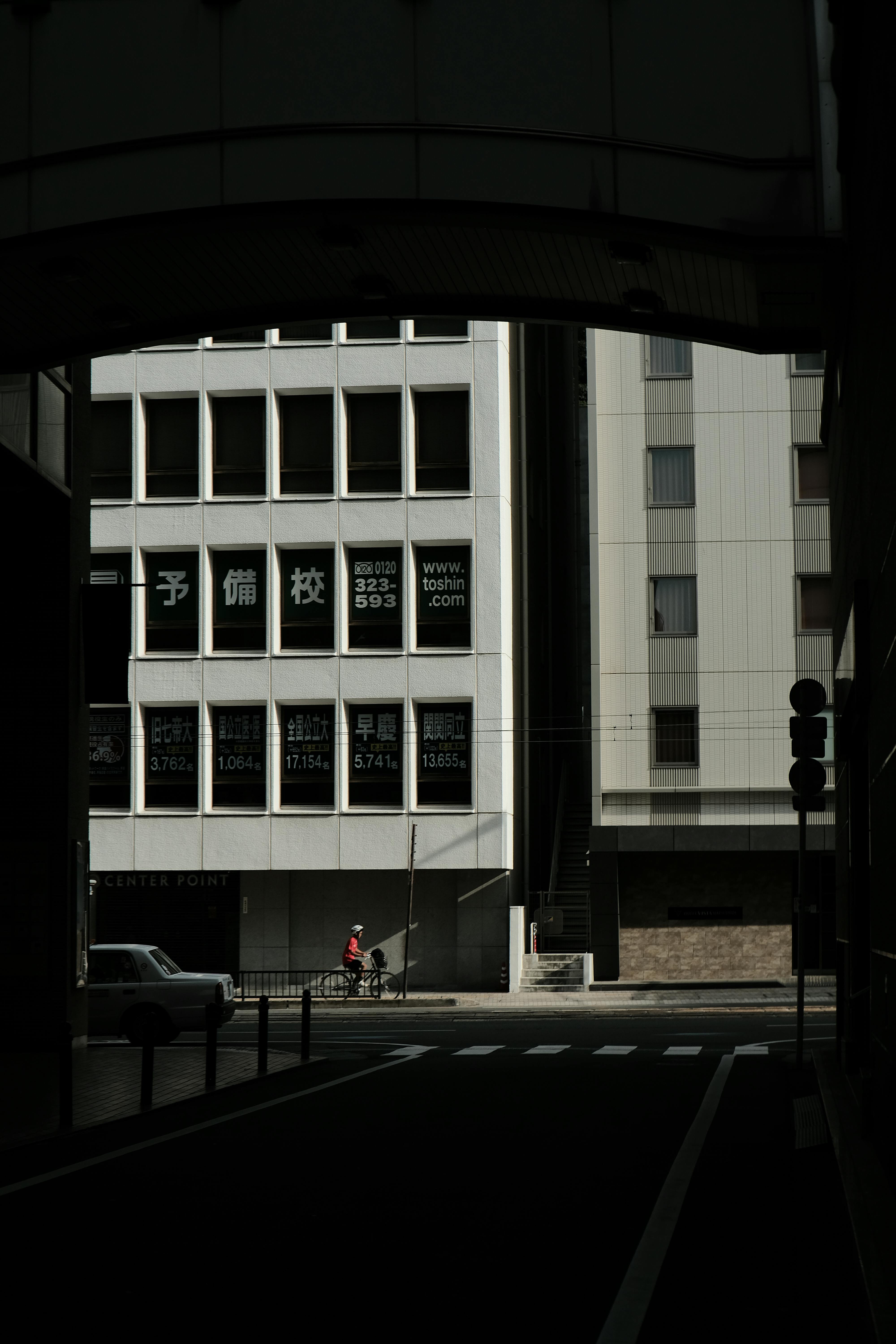 Dramatic urban scene with cyclist framed by building shadows