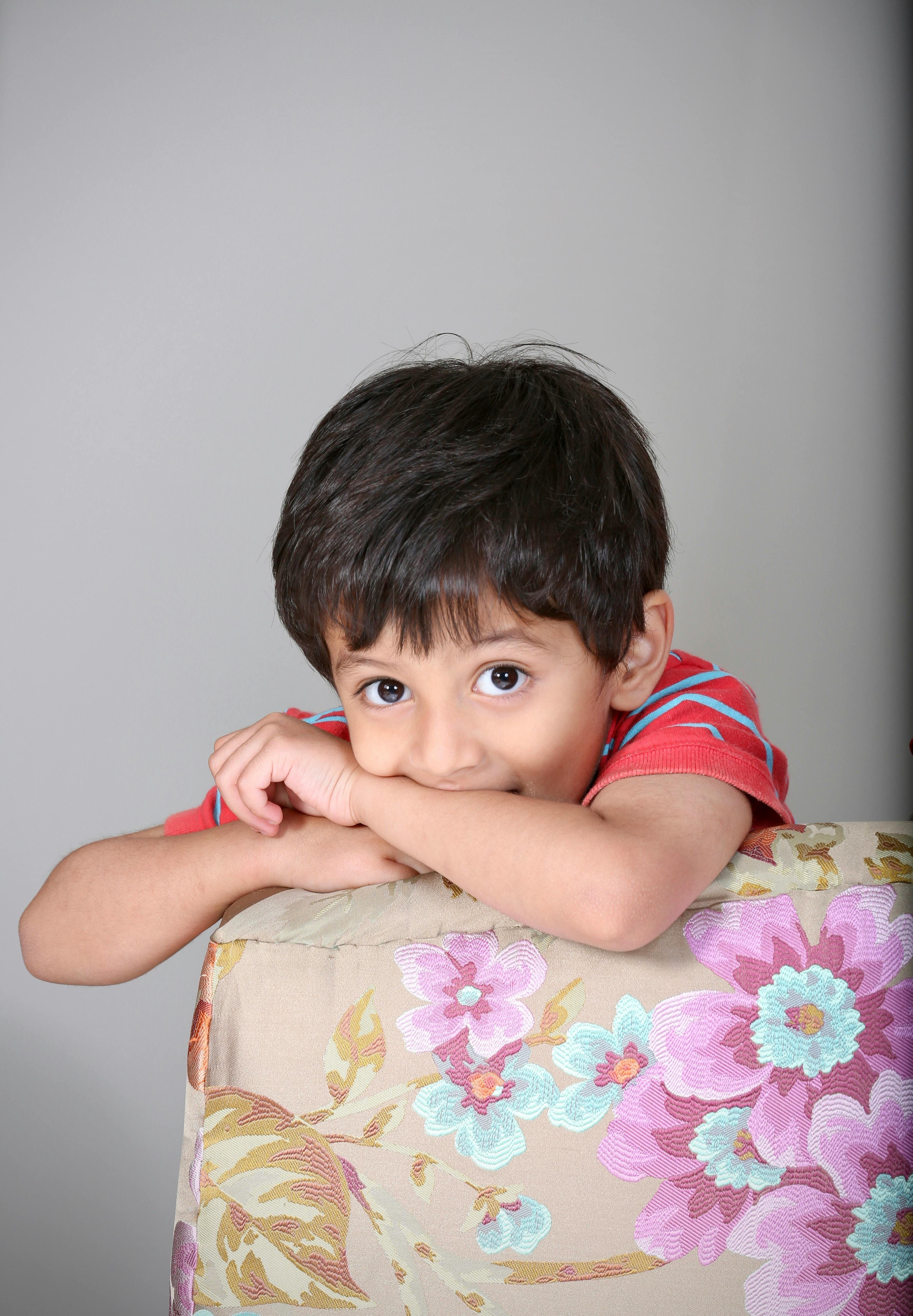Charming portrait of a young child peeking over a floral couch indoors.