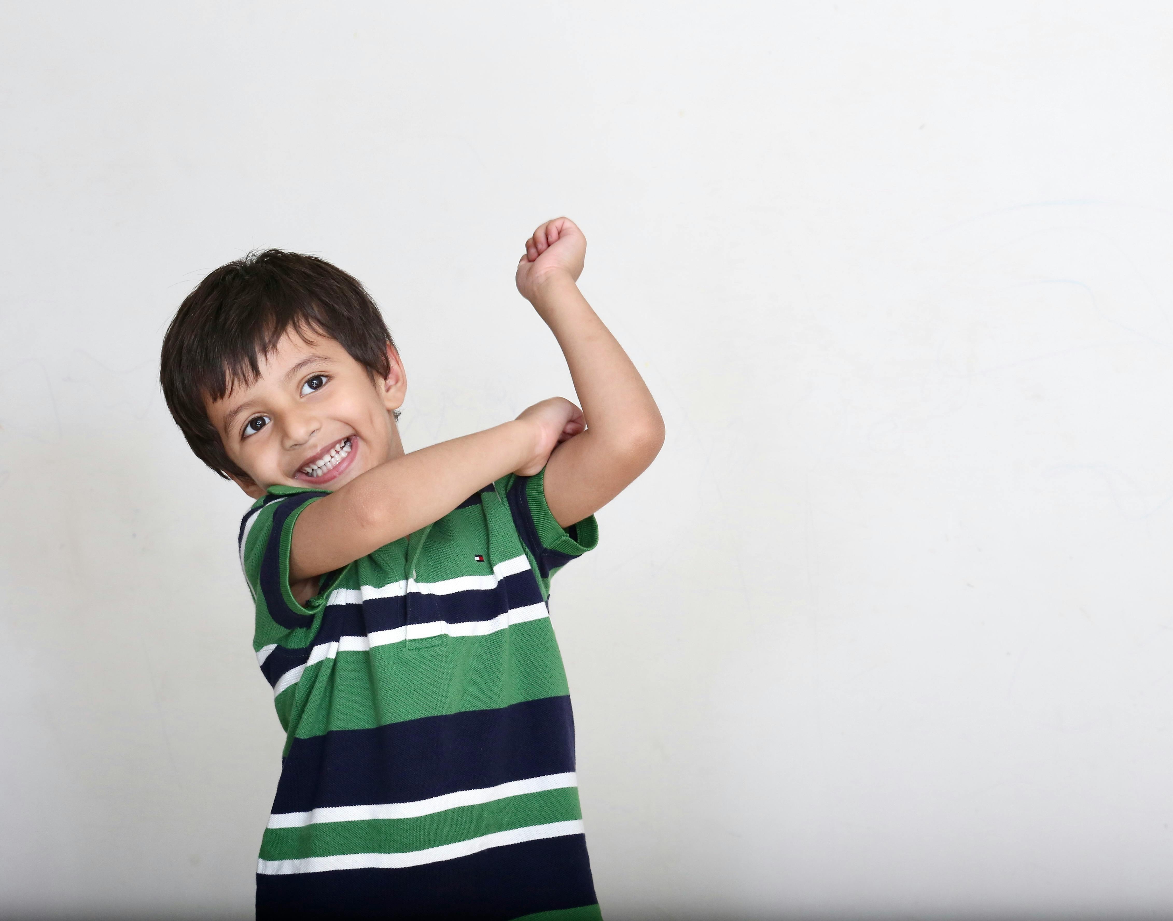 Cheerful child wearing a striped green shirt, posing joyfully.