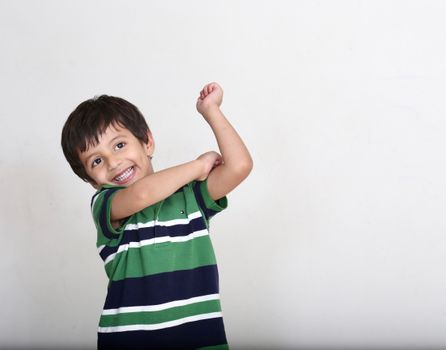 Cheerful child wearing a striped green shirt, posing joyfully.