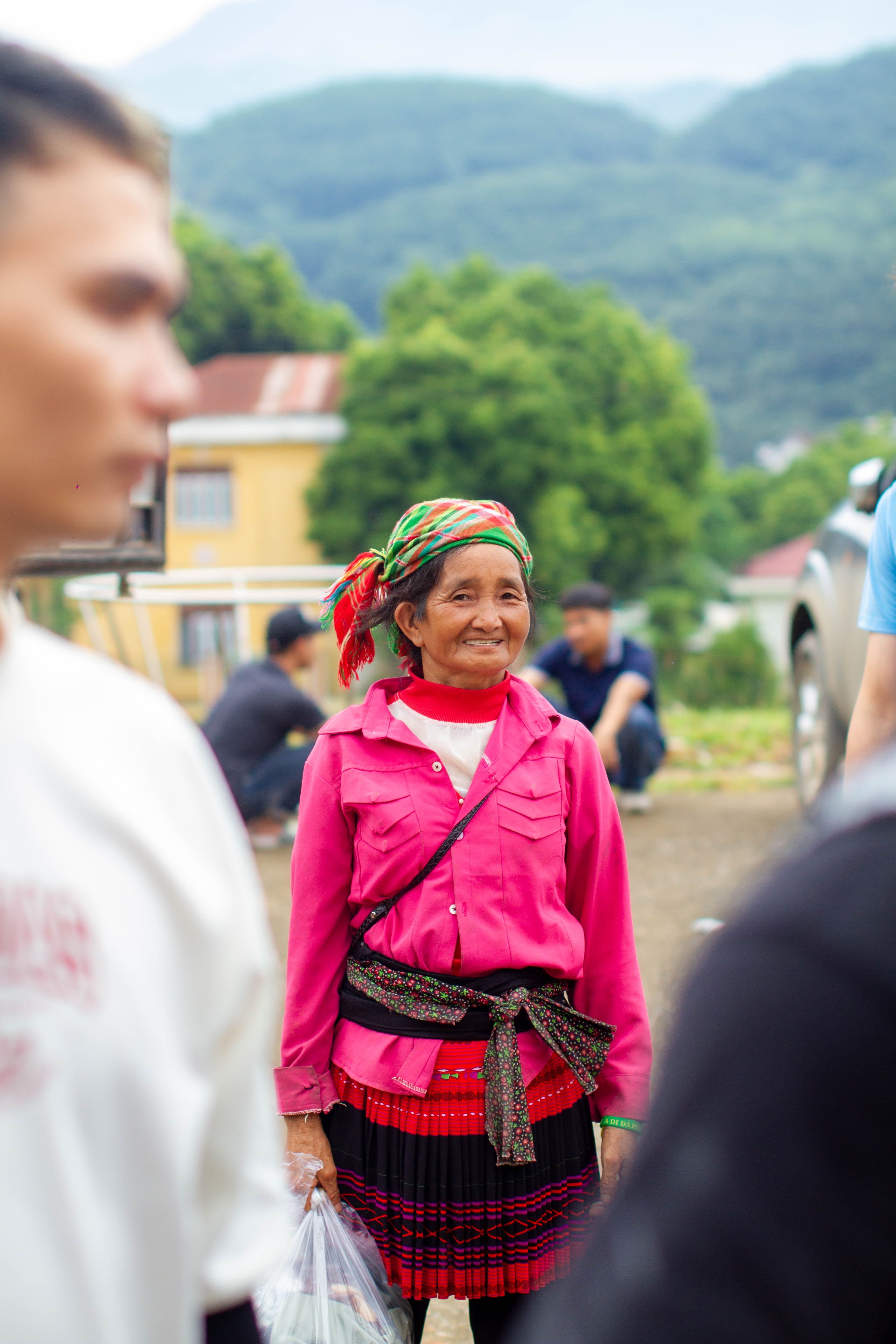 Smiling ethnic woman in bright traditional attire, Lào Cai, Vietnam.