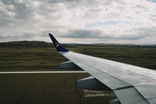 View of an airplane wing over a runway at Oskemen, Kazakhstan, on a cloudy day.