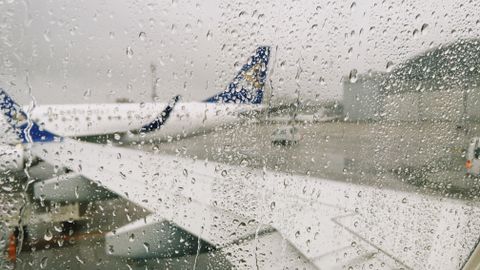 Raindrops on airplane window with a view of the airport in Almaty, Kazakhstan.