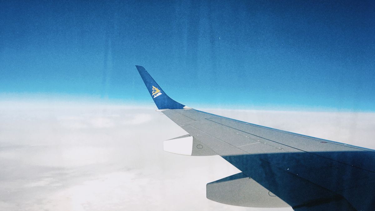 A view of an airplane wing soaring above the clouds under a clear sky, photographed in Kazakhstan.