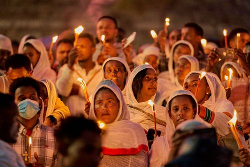 Free A diverse group participates in a solemn candlelight vigil ceremony outdoors at night. Stock Photo