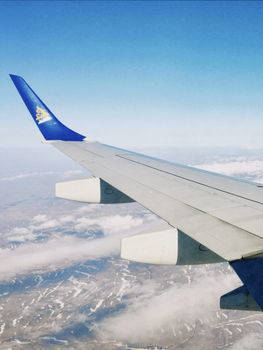 A stunning aerial view of Kazakhstan's landscape from an airplane wing, showcasing clouds and terrain below.