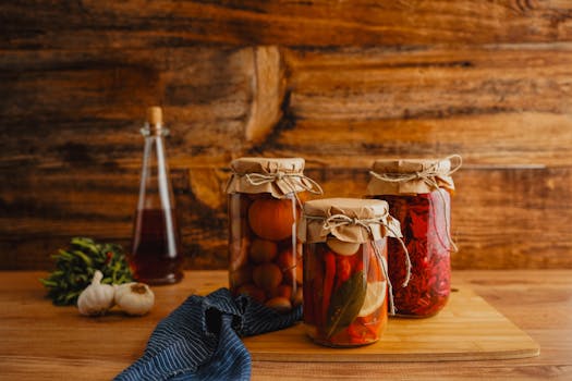 Jars of preserved vegetables on a wooden surface with a rustic background.