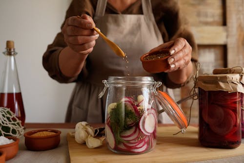 Free Hands preparing pickled vegetables in a jar, capturing a rustic and organic lifestyle. Stock Photo