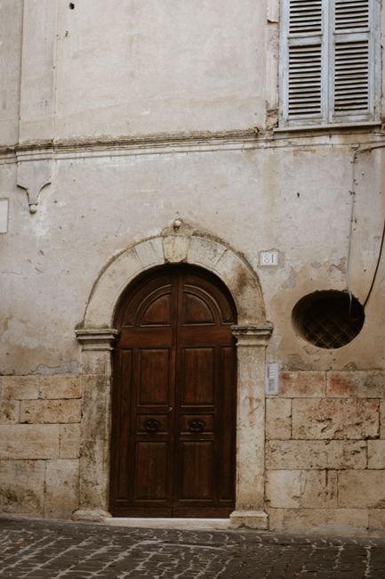 Rustic wooden door set in an aged stone facade, exuding historical charm.