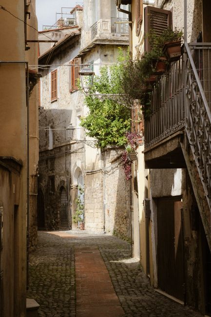 Explore the charming narrow alleyway in a quaint historic European village with cobblestones and rustic architecture.