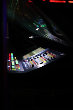 Close-up of a digital audio mixer at a music concert with vibrant lights.