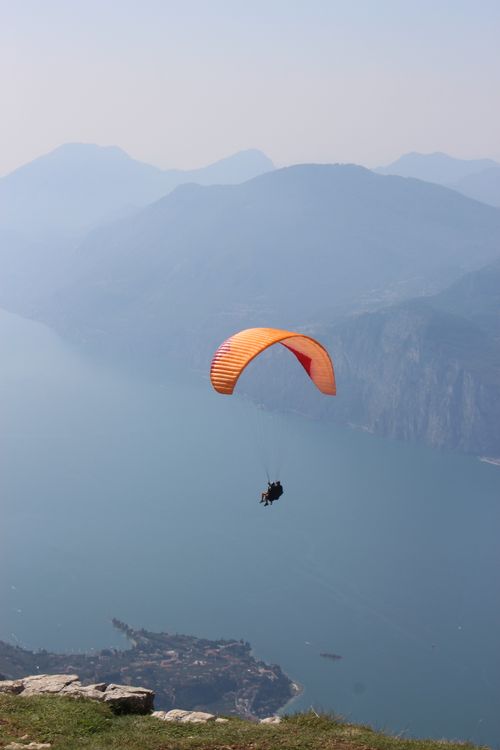 Free A mesmerizing view of a paraglider soaring over Lake Garda with Monte Baldo in the background. Stock Photo