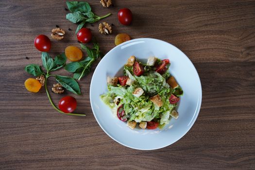 Top-down view of a fresh mixed salad with cherry tomatoes, croutons, and apricots.