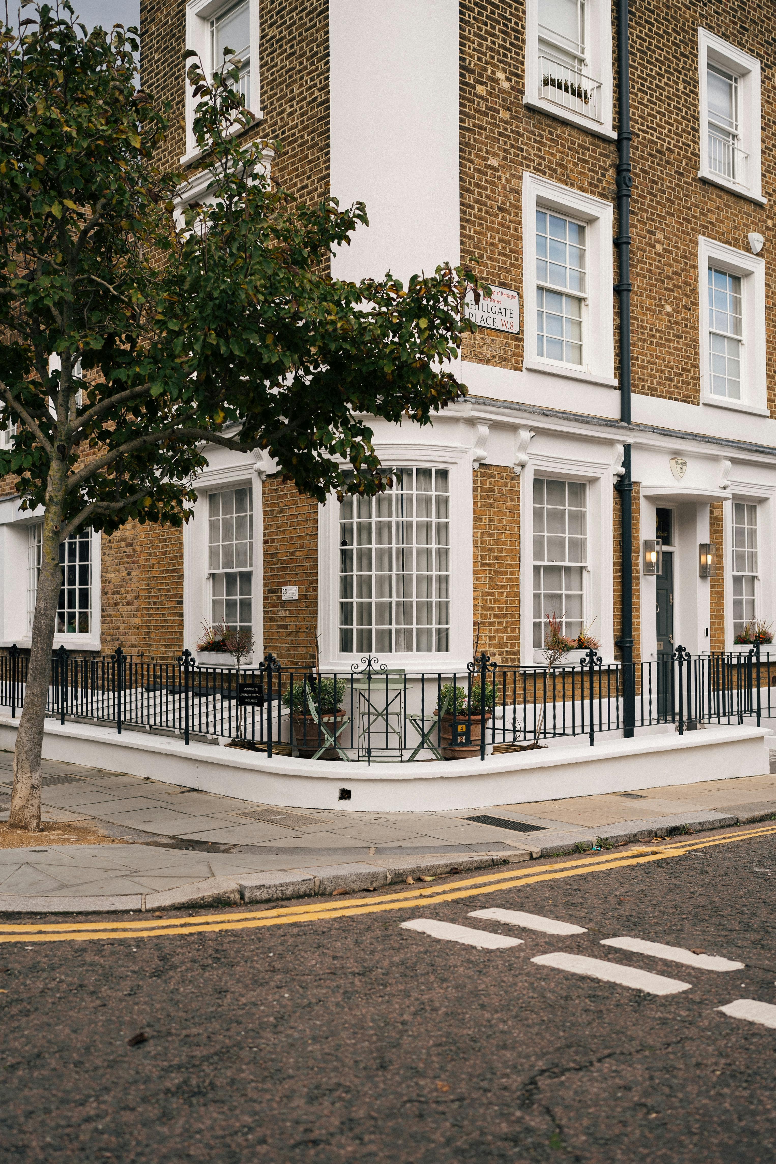 Free Corner view of historic brick building with tree and street in urban area. Stock Photo