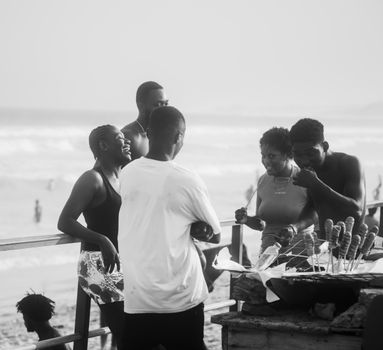 Joyful group enjoying a beachside barbecue on a sunny day, capturing vibrant summer vibes.