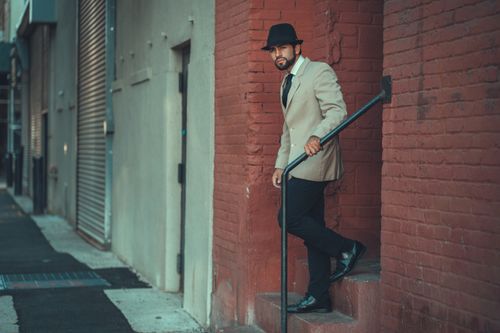 Free Fashionable man in a hat posing elegantly on a New York City street against a brick wall. Stock Photo
