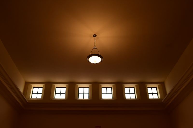 Chandelier hanging from the ceiling in a dimly lit room with symmetrical windows.